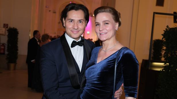 Ein Mann im Smoking umarmt eine Frau in einem blauen Samtkleid.
