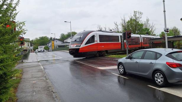Ein ÖBB-Zug überquert einen Bahnübergang bei rotem Licht.