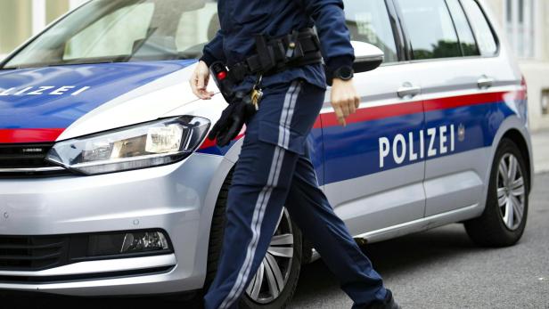 Ein Polizist geht an einem Polizeiauto vorbei.