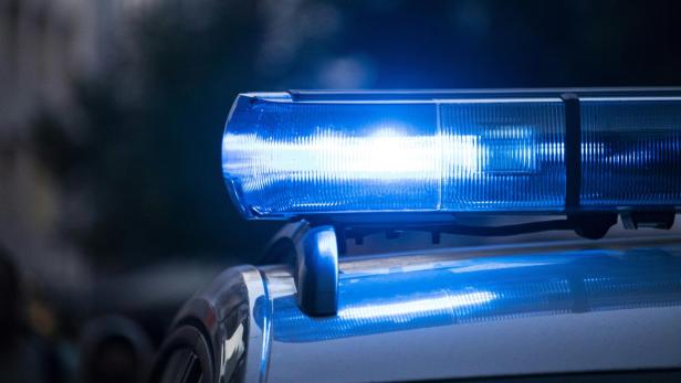 Blaulicht leuchtet auf dem Dach eines Einsatzfahrzeugs im Dunkeln.