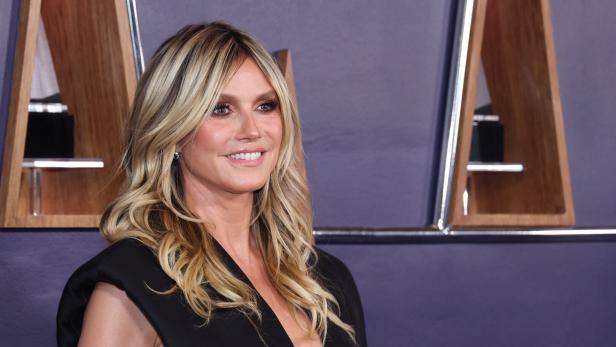 Heidi Klum lächelt in einem schwarzen Kleid.