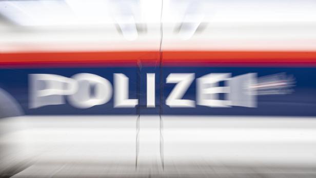 Verwischte Aufnahme eines Polizeiautos mit der Aufschrift "POLIZEI" in Weiß auf blauem Grund.
