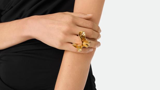 Zwei verschränkte Hände mit einem goldenen auffälligen Ring auf einer Hand