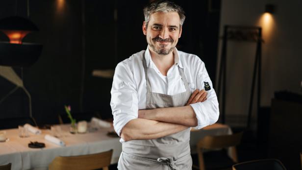 Manuel Ressi, der Koch vom Bärenwirt,  mit verschränkten Armen steht vor einem gedeckten Tisch.