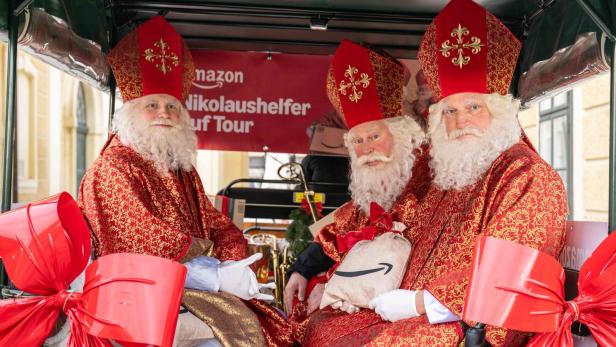 Drei als Nikolaus verkleidete Männer mit roten Mänteln und Bischofsmützen sitzen in einer festlich geschmückten Kutsche.