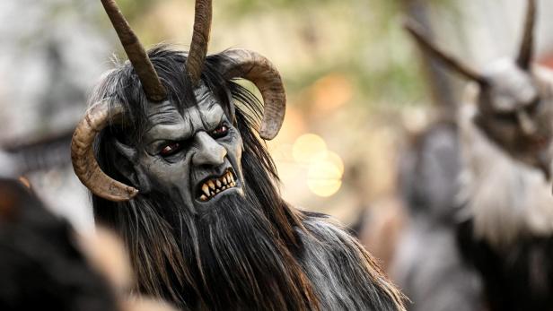 Eine gruselige Krampus-Maske mit Hörnern, Fell und fletschenden Zähnen ist zu sehen.