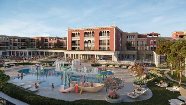 Vor einem großen, venezianisch wirkenden Gebäude entspannen Menschen auf Liegen und spielen Kinder in einem Pool mit Wasserspielen und Rutsche.