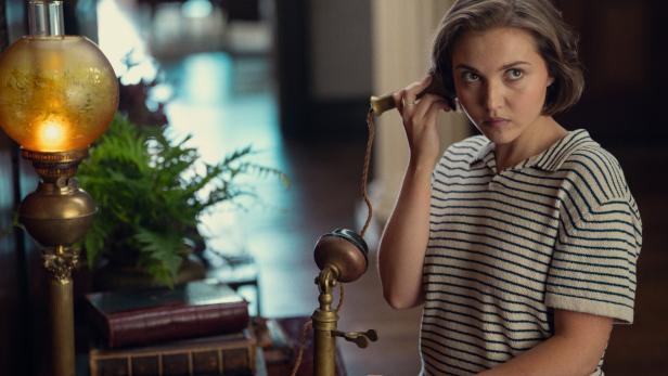 Lady Eileen, genannt Bundle (Mia McKenna-Bruce), telefoniert mit einem Informanten in der Netflix-Serie „Agatha Christie’s Seven Dials“.