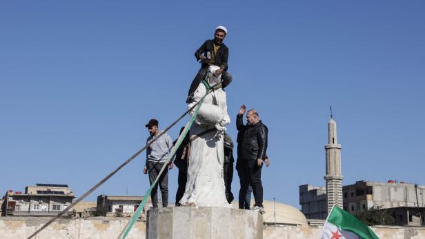 Araber  feiern die Vorstöße: Im Bild stürzen sie eine Statue der  kurdischen Frauenmiliz in ar-Raqqa.