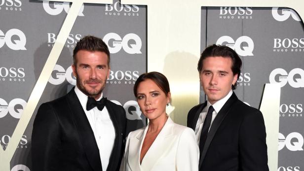 David Beckham, Victoria Beckham und ihr Sohn Brooklyn posieren gemeinsam im eleganten Outfit auf dem roten Teppich bei einer GQ-Veranstaltung.