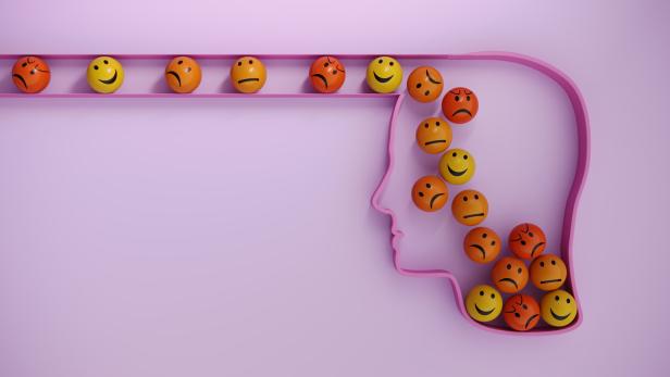 Mehrere Kugeln mit verschiedenen Gesichtsausdrücken rollen in einen stilisierten menschlichen Kopf.