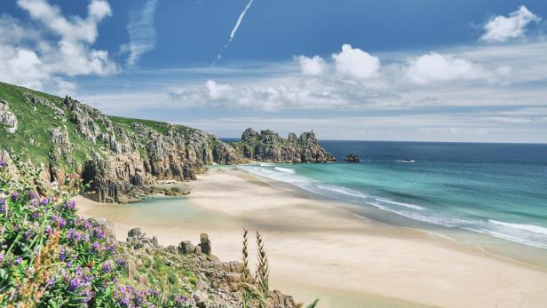 Scenic views across Pedn Vounder Beach towards Logan's Rock, Cornwall on a sunny June day.