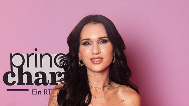 Vanessa "Nessi" Borck lächelt. Sie steht vor einem rosa Hintergrund.