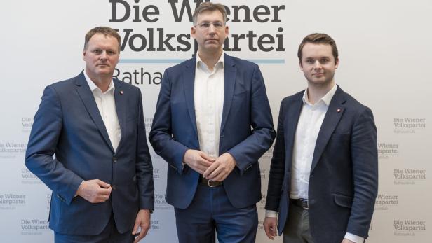 Drei Männer in Anzügen stehen nebeneinander vor einer Wand mit dem Schriftzug „Die Wiener Volkspartei“.