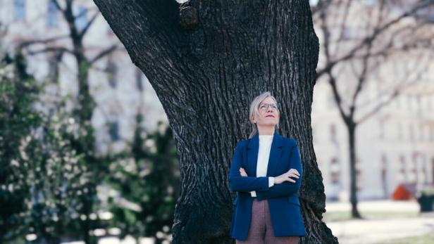 Grünen-Chefin Leonore Gewessler lehnt sich an einen Baum vor dem Parlament