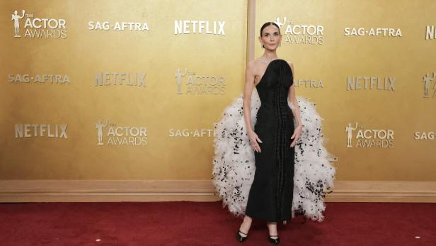 Demi Moore in einem schwarzen Kleid mit Federn auf dem roten Teppich.