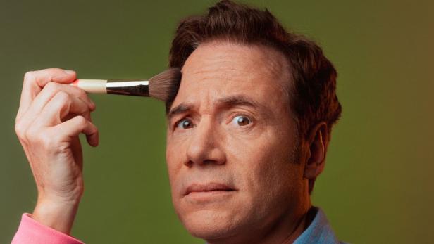 Michael Bully Herbig blickt ernst mit Schminkpinsel im Gesicht