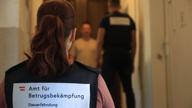 Steuerfahnder stehen vor einem Mann