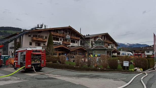 Feuerwehreinsatz mit Löschfahrzeugen und Schläuchen vor einem Hotel in Tirol.