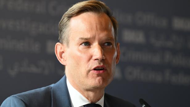 Virologe Hendrik Streeck im Anzug spricht vor einem dunklen Hintergrund mit Schrift.