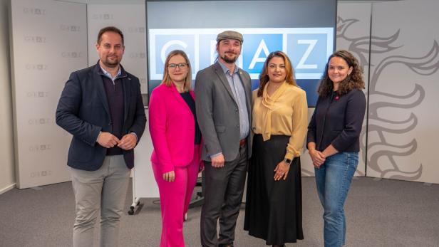 Fünf Personen posieren vor einem Bildschirm mit dem Schriftzug "GRAZ".