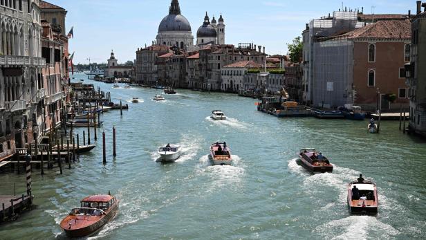Mehrere Boote fahren auf dem Canal Grande in Venedig vor der Kuppel der Kirche Santa Maria della Salute.