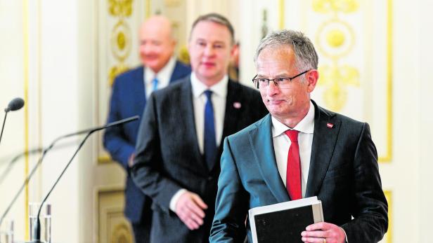 Finanzminister Markus Marterbauer geht in einen Raum, hinter ihm Vizekanzler unscharf Andreas Babler