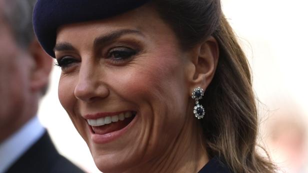 Prinzessin Kate, mit Hut und Ohrringen, lächelt.