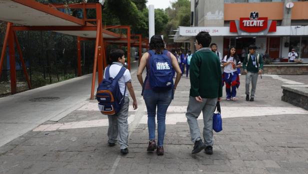 Drei mexikanische Schüler vor einer Schule.