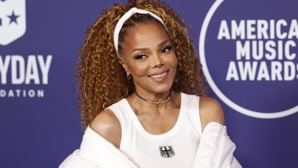 Janet Jackson lächelt vor einem Hintergrund der American Music Awards.