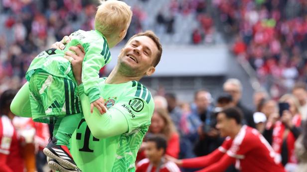 Manuel Neuer hebt ein Kind in die Höhe.