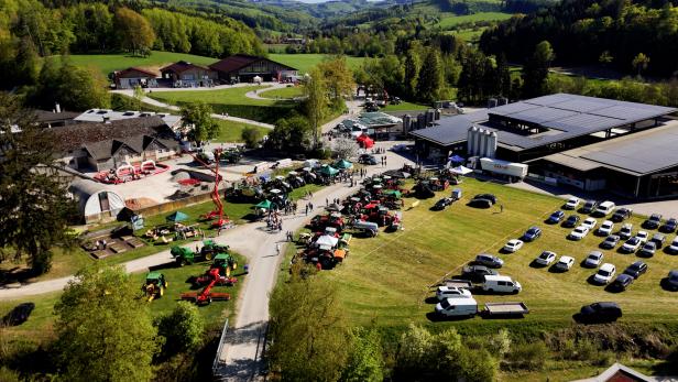 Luftaufnahme der Landwirtschaftlichen Fachschule Pyhra mit zahlreichen landwirtschaftlichen Maschinen, Besuchern und geparkten Autos bei einer Veranstaltung auf dem Schulgelände.