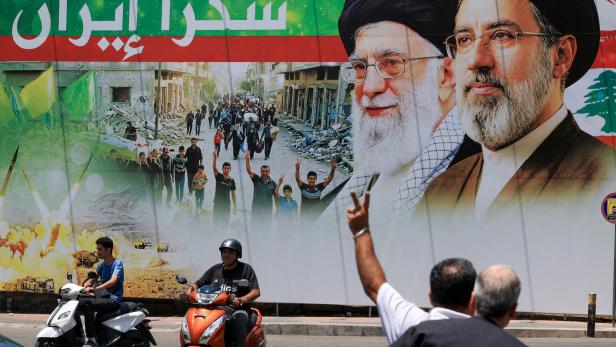 A man flashes a victory sign as he rides a motorcycle past a banner that reads "Thank you Iran" following a deal between the U.S. and Iran, in Beirut