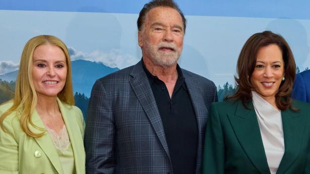 Heather Milligan, Arnold Schwarzenegger und Kamala Harris stehen nebeneinander vor einem Hintergrund mit Foto von Berglandschaft.