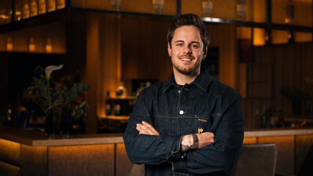 Bartender of the Year 2026 Yannik Seeber steht lächelnd vor einer Bar. 