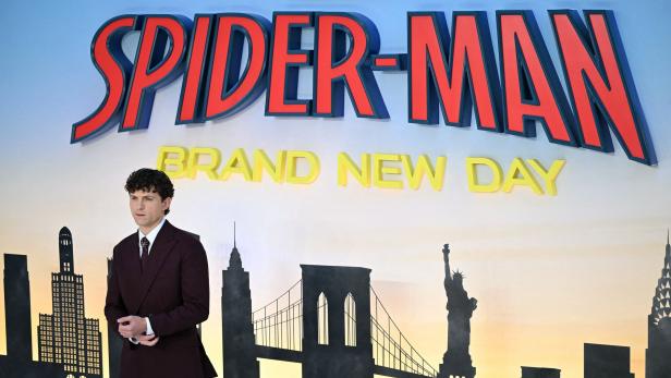 Tom Holland steht vor dem Schriftzug „Spider-Man: Brand New Day“ vor einer New-York-Skyline.