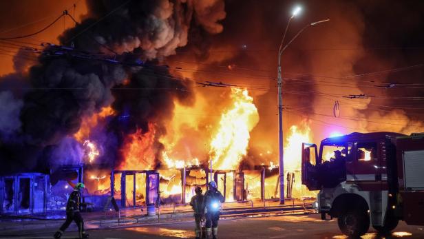 Großbrand eines Gebäudes mit meterhohen Flammen, dichtem Rauch und Feuerwehrleuten im Einsatz.