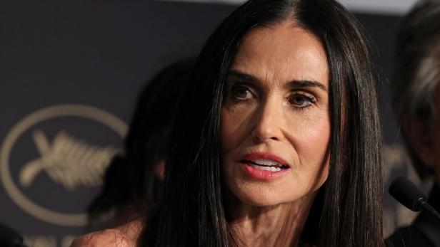 Demi Moore spricht vor einem Mikrofon vor dem Logo der Filmfestspiele von Cannes.