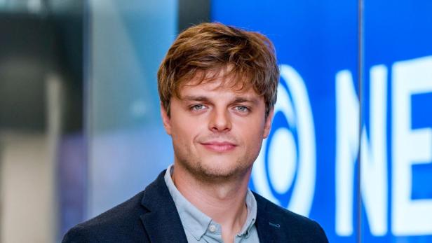 ORF-Beirut-Leiter Paul Huemer im dunklen Blazer und hellblauen Hemd steht vor einem blauen Hintergrund.