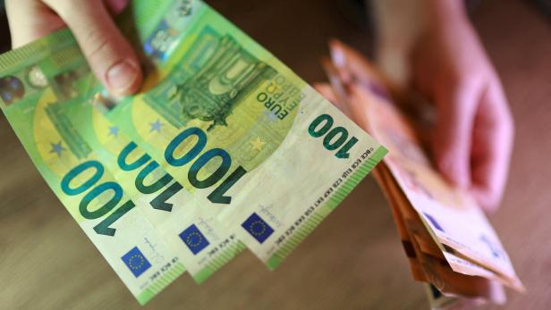 Hände zählen mehrere 100-Euro-Scheine.