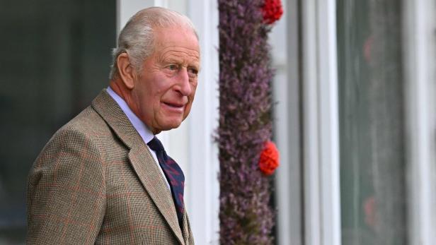 König Charles III. trägt ein kariertes Tweed-Sakko und blickt zur Seite.