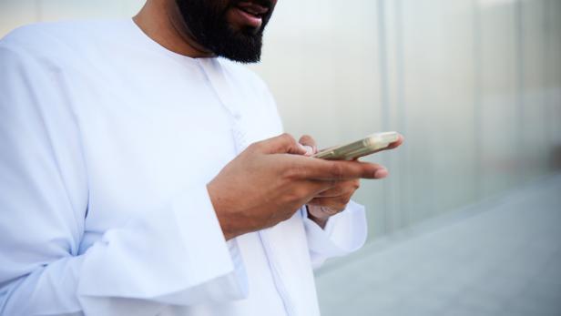 In the street, a man is texting on his smartphone and checking social media.