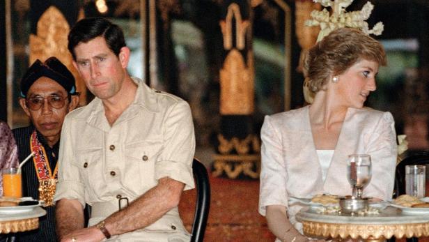 König Charles III. und Prinzessin Diana sitzen bei einem offiziellen Anlass nebeneinander an kleinen Tischen.