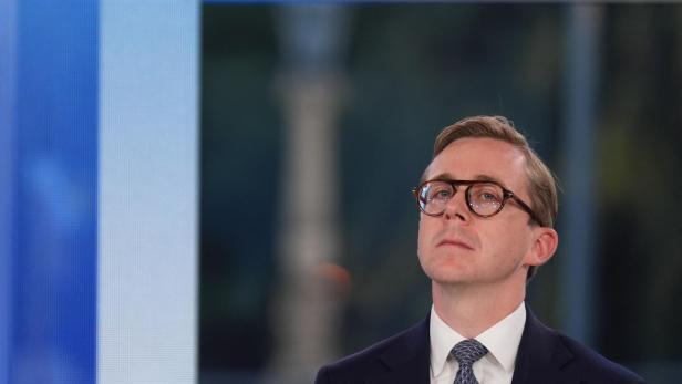 Mann im Anzug mit Brille und Krawatte blickt ernst nach oben.