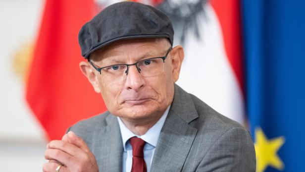 Finanzminister Markus Marterbauer, SPÖ, mit Anzug und Kappe vor Österreich-Fahne anlässlich eines Ministerrats
