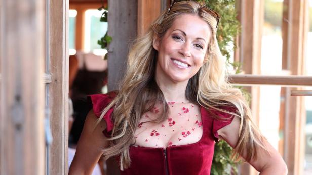 Andrea Kaiser lächelt in einem roten Kleid an einer Holzbrüstung.