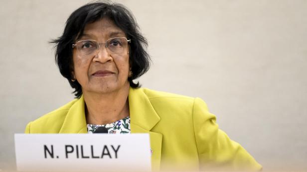 Navi Pillay in gelbem Blazer, hinter einem Schild mit Aufschrift "N. PILLAY".