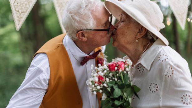 Senior couple having marriage, kissing in nature during summer day.