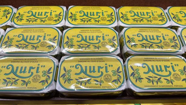 Mehrere gelbe Sardinen-Dosen mit der Aufschrift „Nuri“ liegen nebeneinander im Regal.