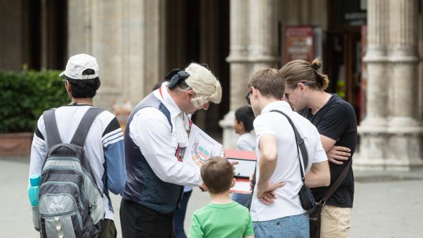 Ein als Mozart verkleideter Verkäufer bietet Touristen Karten an.